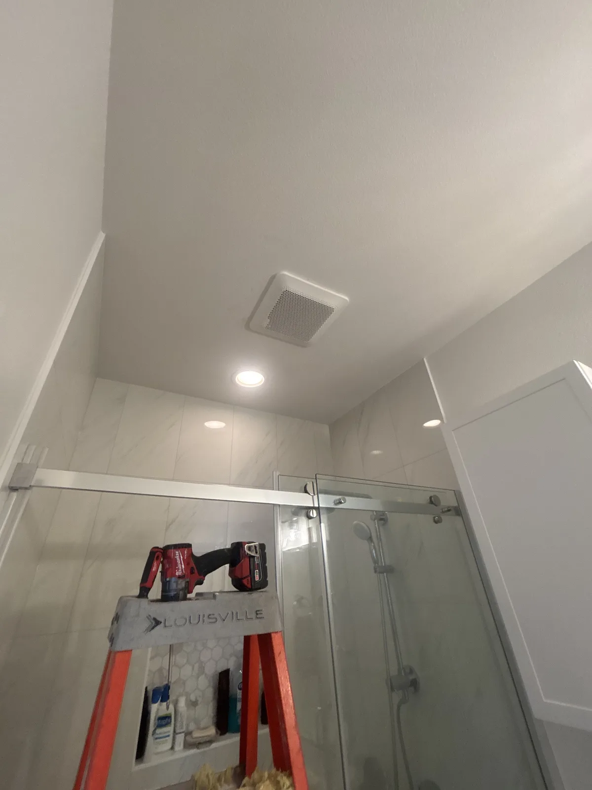 New bathroom exhaust fan and recessed light in a bathroom ceiling during installation
