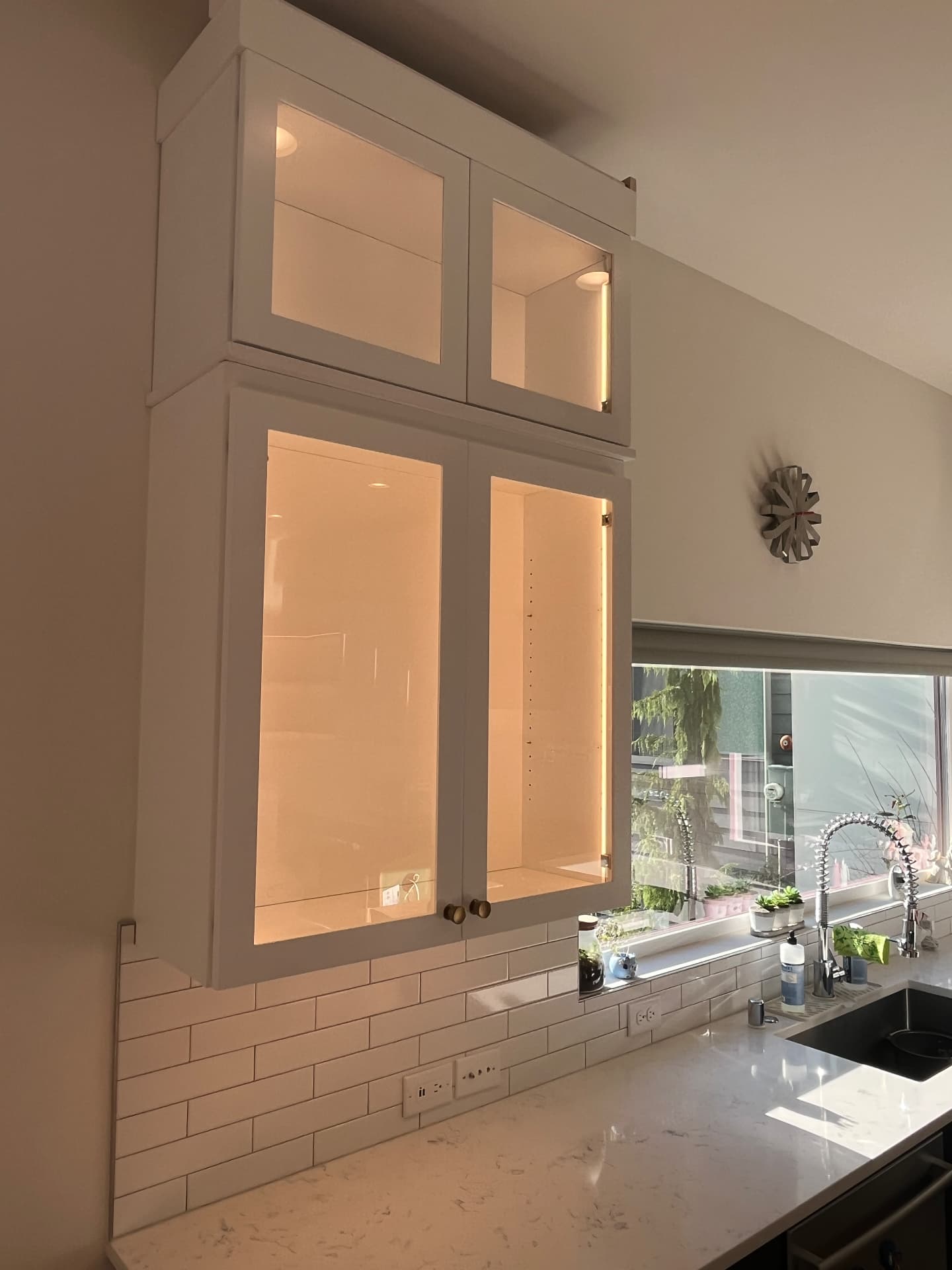 Warm illuminated glass-front kitchen cabinets above a counter