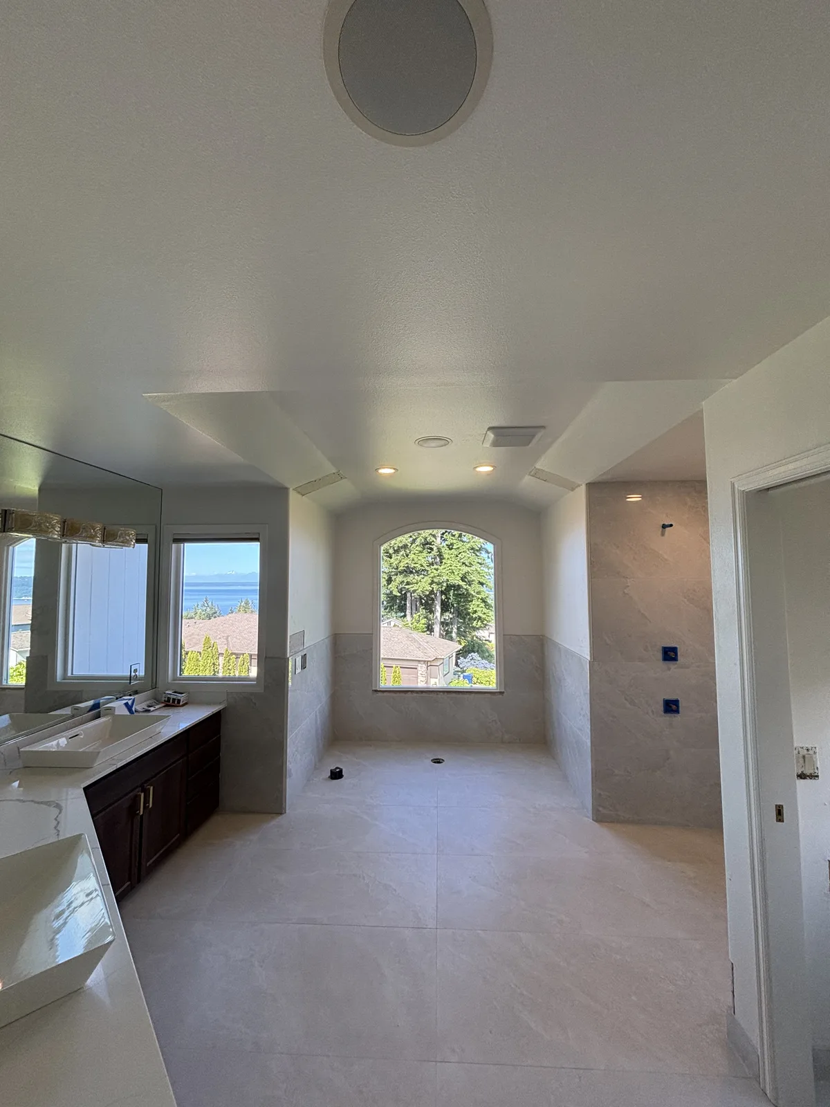 Hallway and bathroom vestibule with recessed ceiling lights beside an arched window