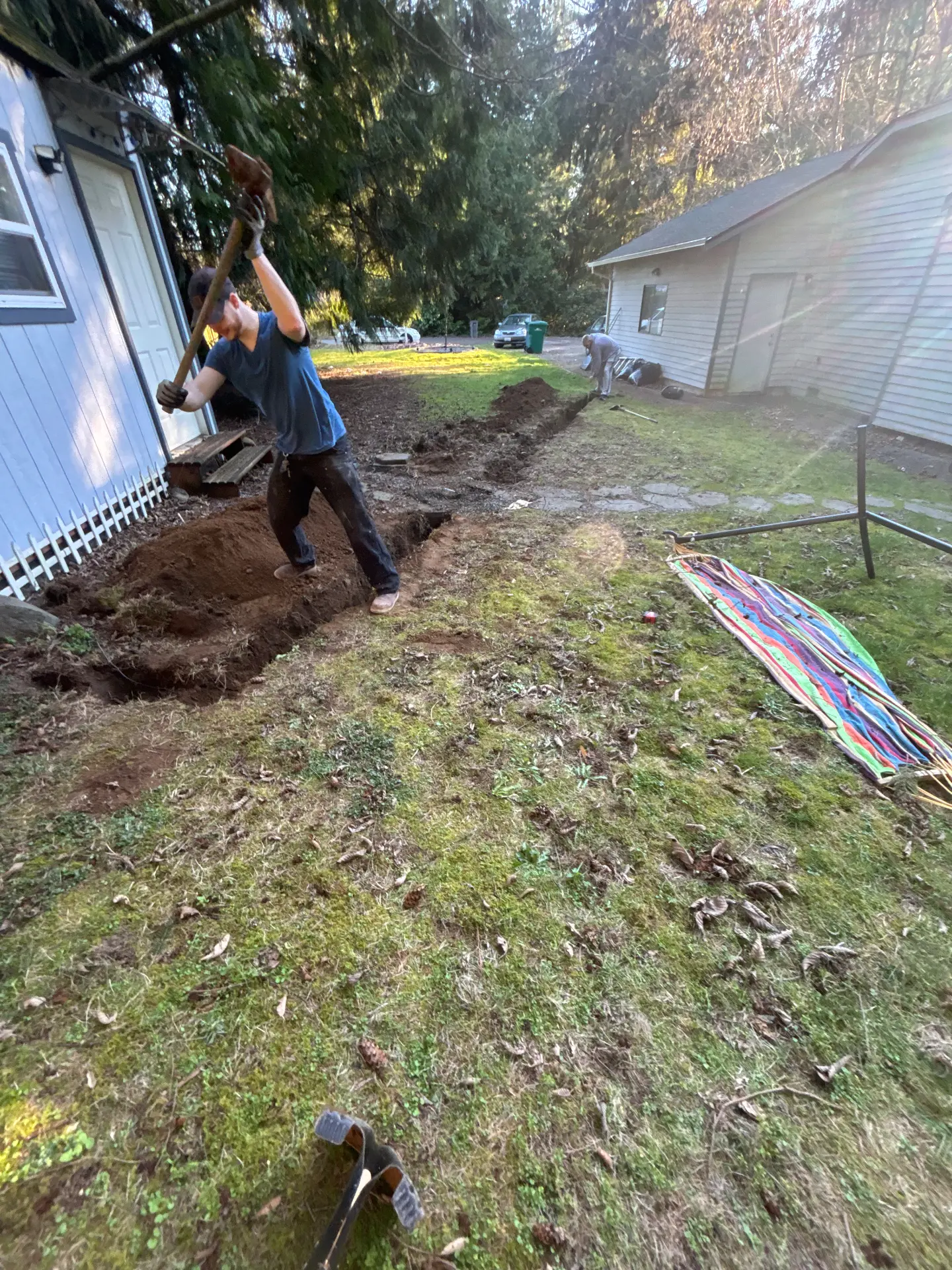 Trenching in progress between a house and a detached shed for a subpanel roughly 70 feet away