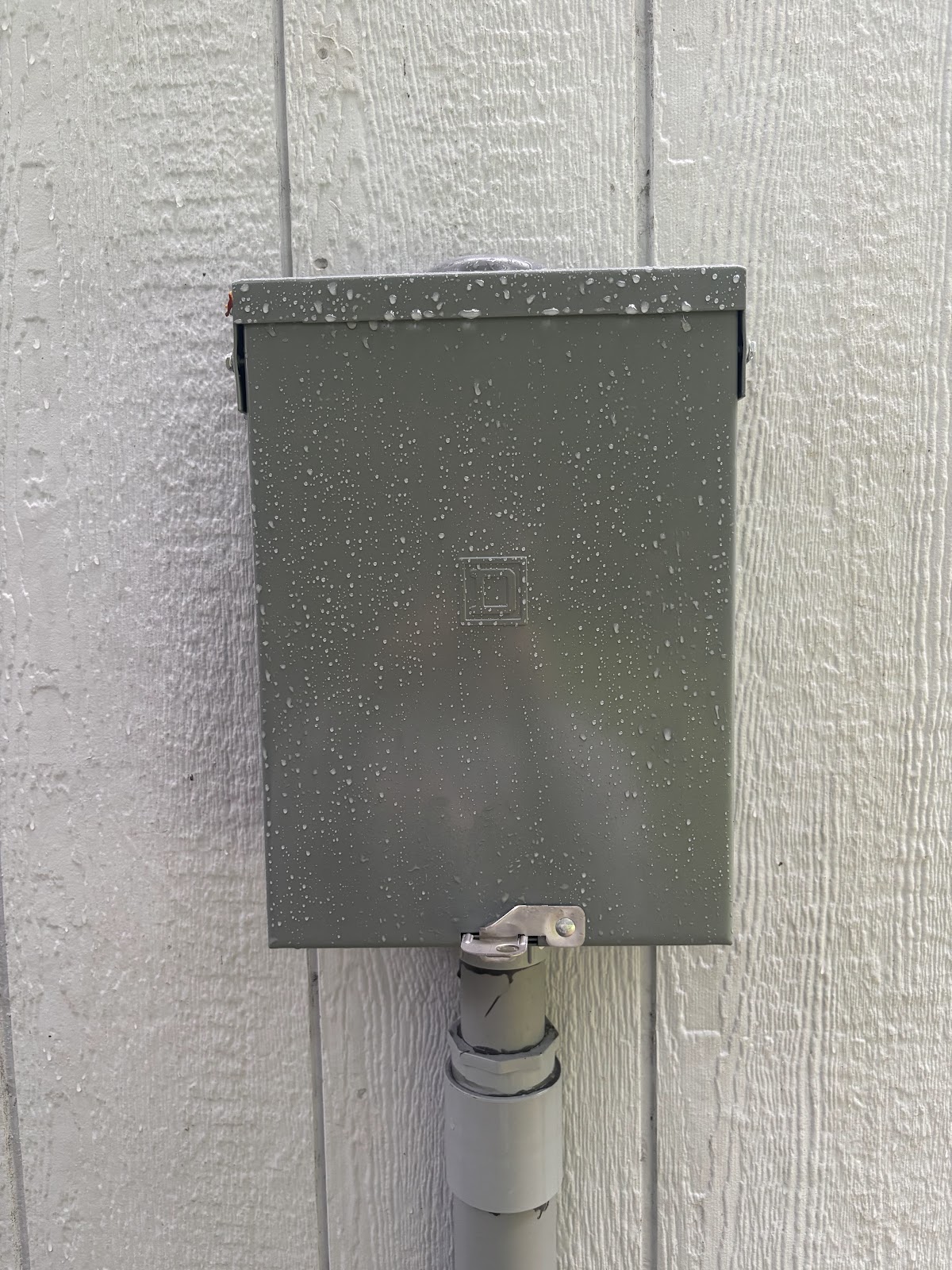 Closed gray electrical panel enclosure on a finished wall