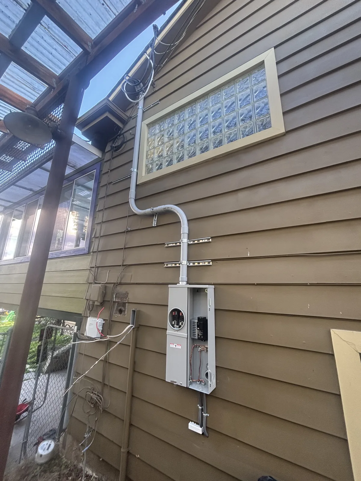 Exterior electrical disconnect box with conduit route under a covered patio